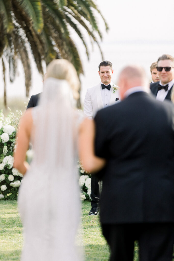 Groom holding back tears as his bride walks down the aisle at the Bacara