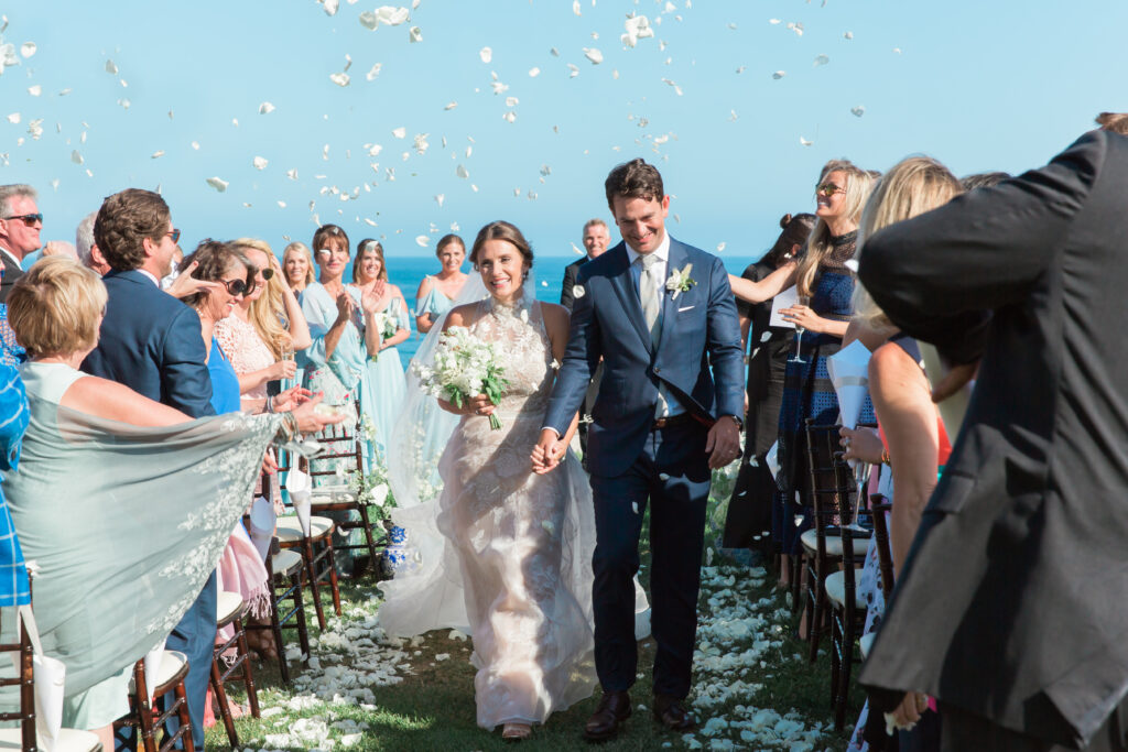 Bride and groom walk down the aisle with rose pedals being tossed at the Bacara 